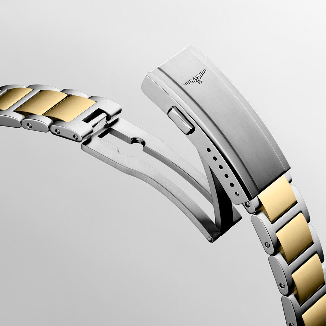 A close-up of the Longines HydroConquest Quartz 42mm Watch bracelet showcases a two-tone metal design with silver and gold links, secured by a deployment clasp engraved with the Longines logo—an elegant tribute to Swiss watchmaking expertise. Set against a plain gray background, this refined detail exemplifies the precision and sophisticated style that defines the Longines HydroConquest collection among sport watches.