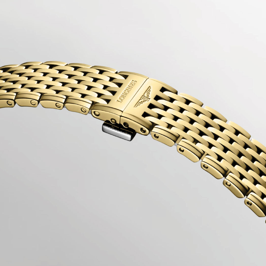 Close-up of the gold metal Longines La Grande Classique De Longines Quartz 39mm watch bracelet, featuring a clasp engraved with the Longines logo and winged hourglass emblem, set against a plain light gray background.