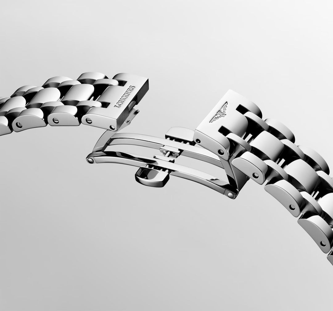 Close-up of a stainless steel Longines Dolcevita Quartz 20.8 x 32mm watch bracelet with a butterfly clasp, featuring polished links and engraved logos—highlighting the refined elegance of this Longines timepiece against a plain, light background.