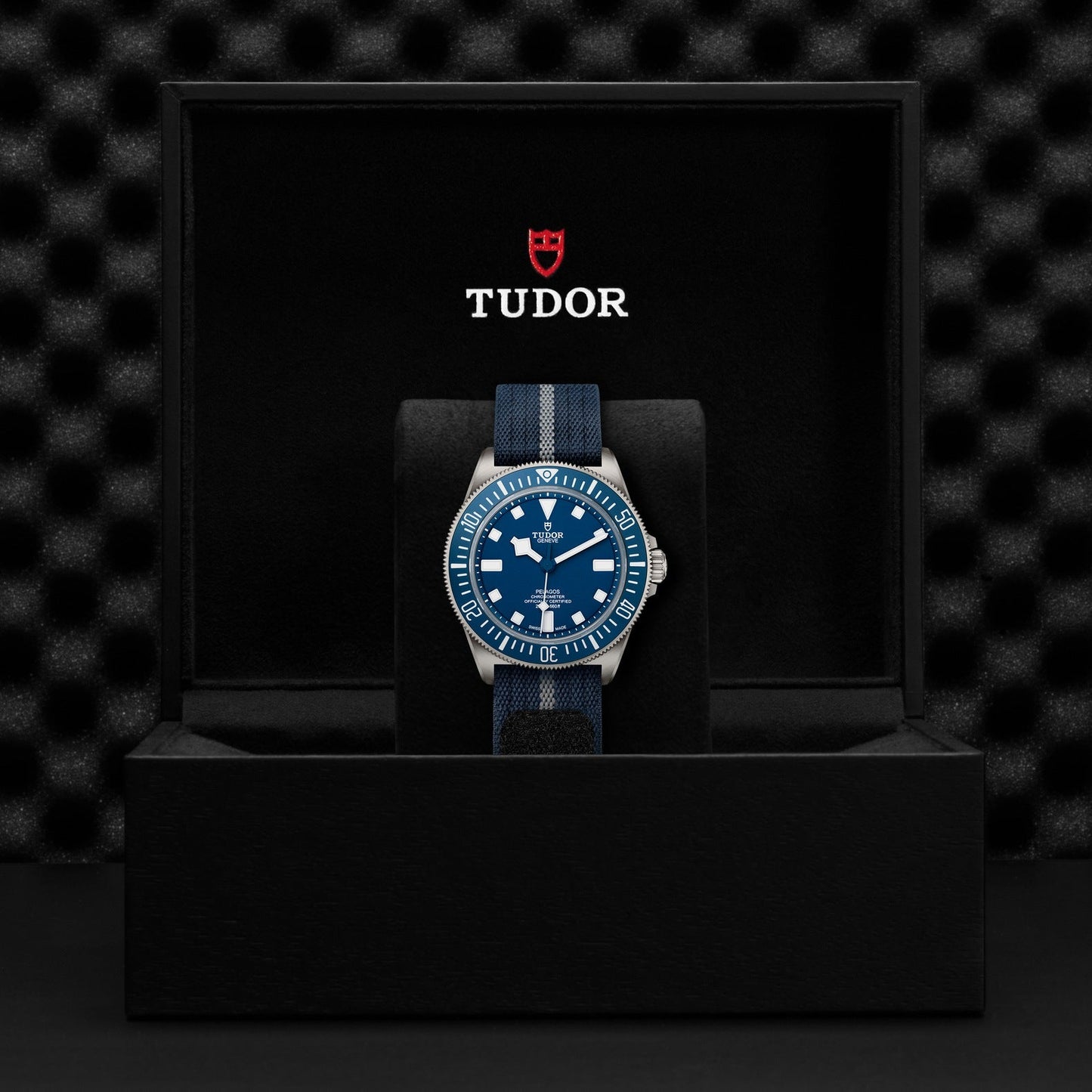 The TUDOR Pelagos FXD, taking inspiration from the Military Submariner, features a striking blue face and bezel and comes packaged in a sophisticated black box. Inside, the watch rests on a soft, textured lining, with "TUDOR" and its logo elegantly showcased on the interior lid.