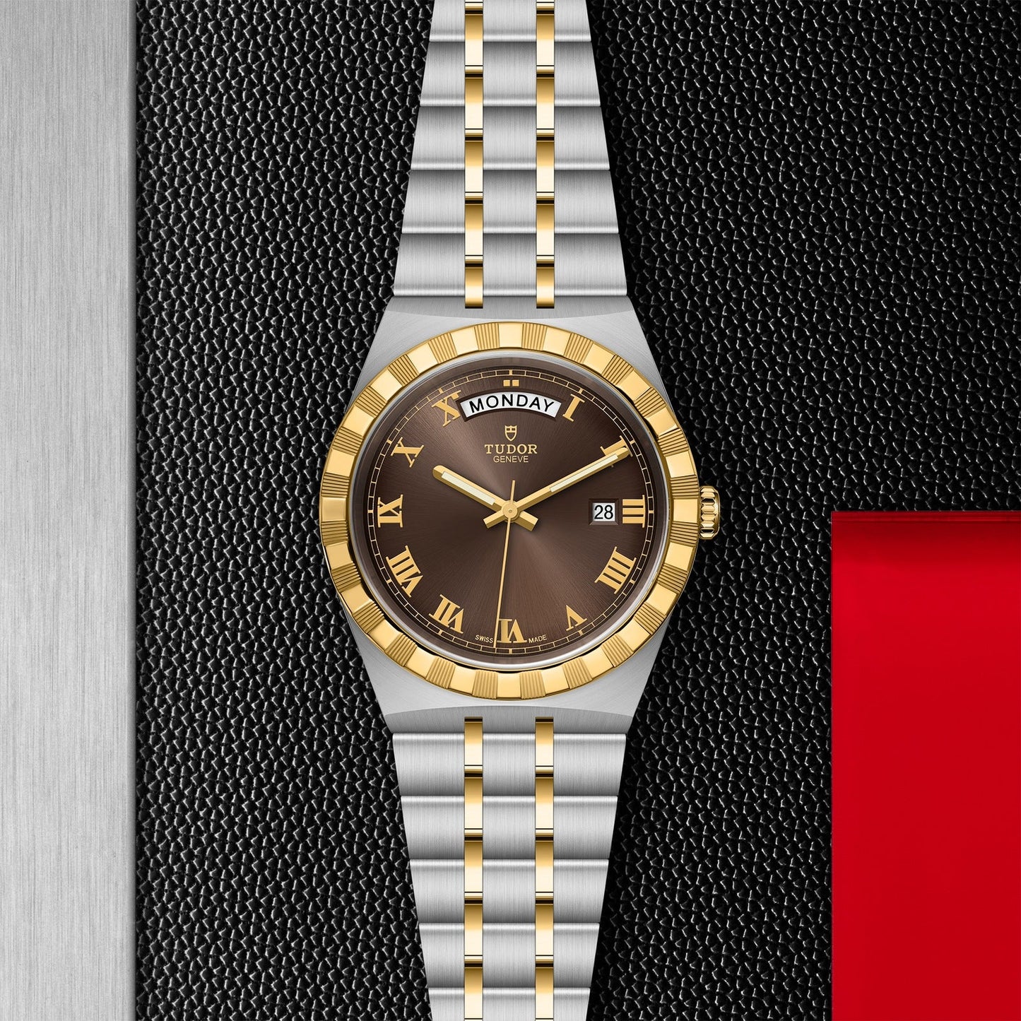 The TUDOR Royal wristwatch from TUDOR showcases a stainless steel and gold band, complemented by a textured black dial adorned with Roman numerals. Its sporty yet chic automatic design includes a day and date display, enhanced by a distinctive touch of red on the side.