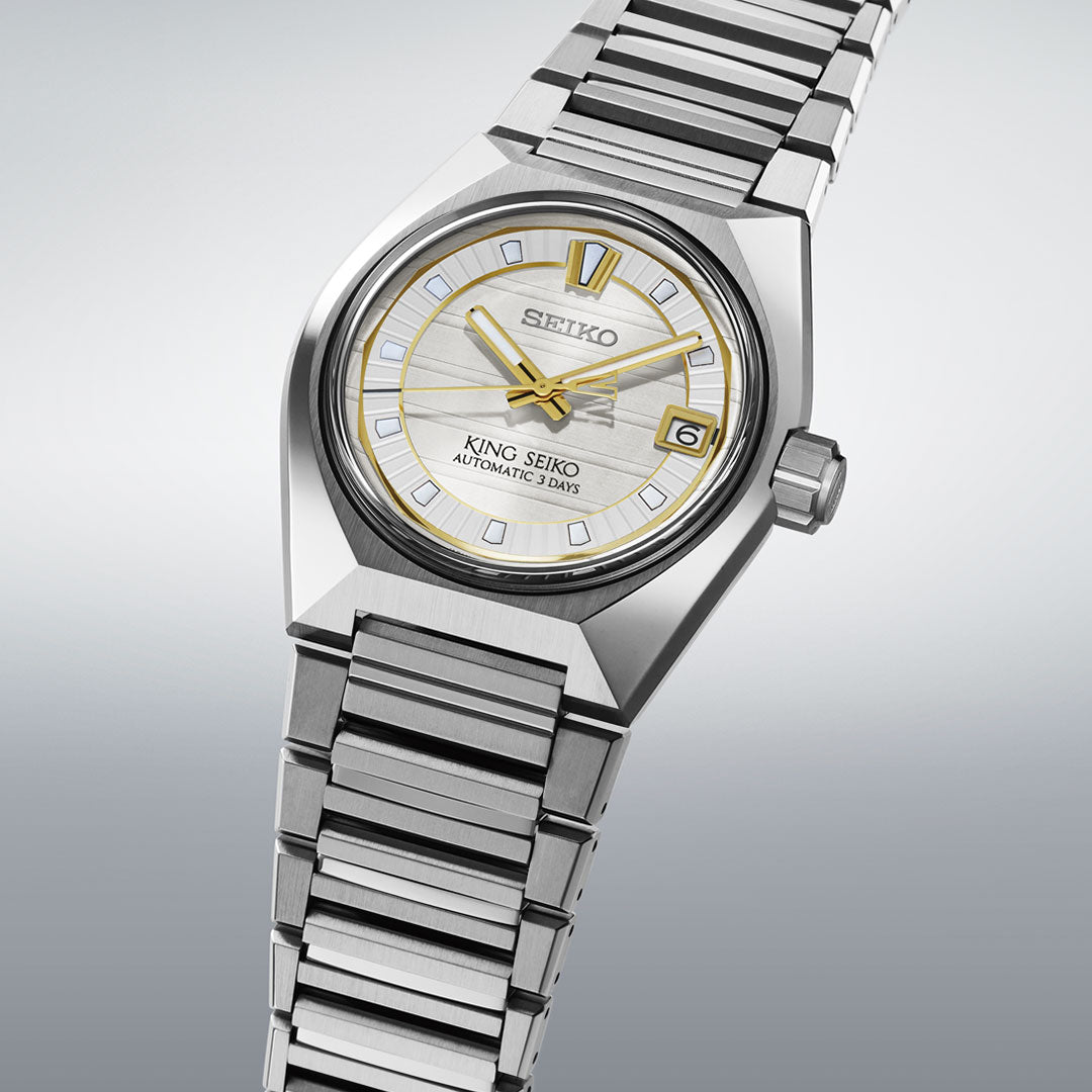 The Seiko King Seiko Vanac Automatic with Manual Winding 41mm Watch features a silver metallic band, gold-accented hands and hour markers, and a date display at 3 o'clock, set on a light gray gradient background.