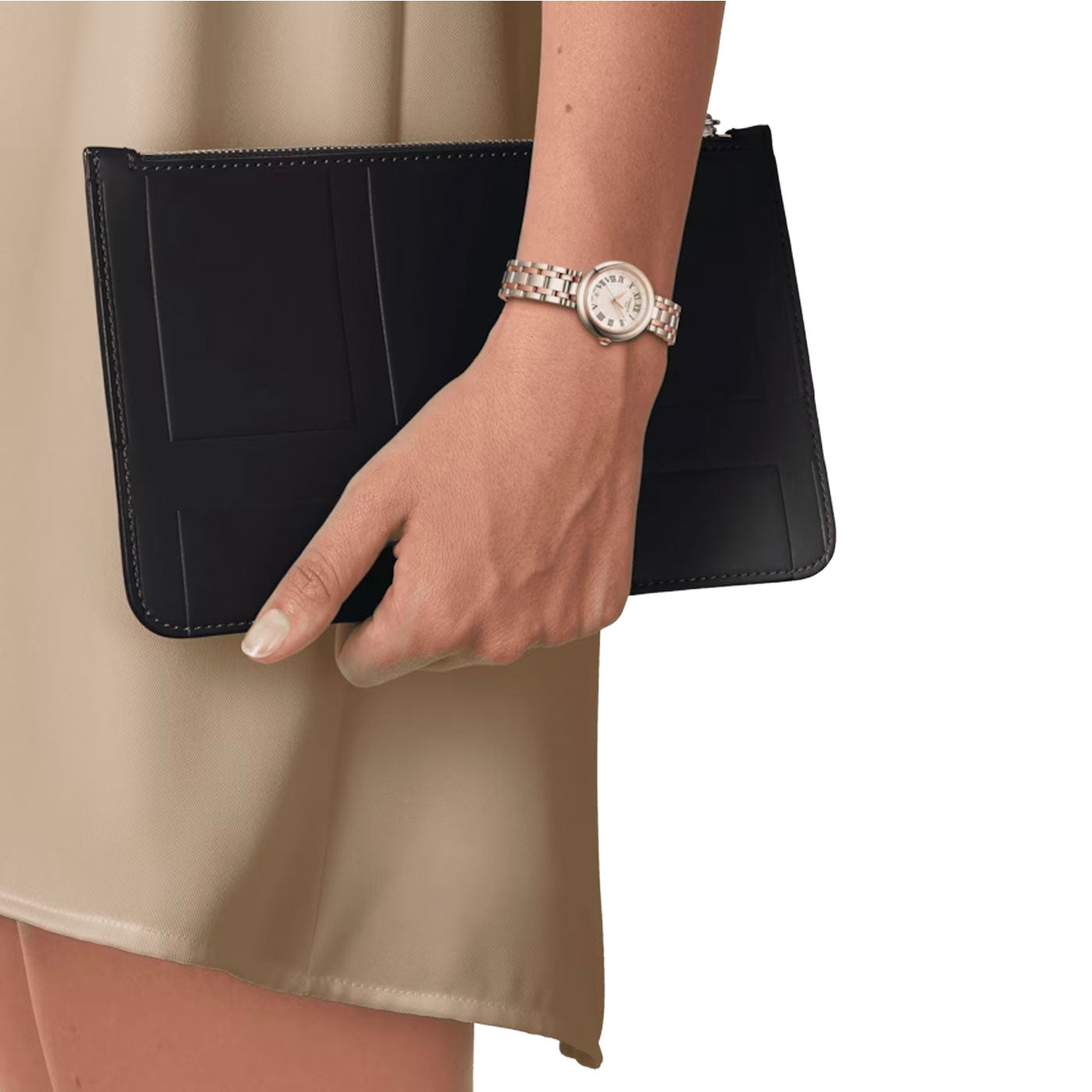 A person wearing a beige dress holds a black clutch bag while sporting a Tissot Bellissima Small Lady Quartz 26mm Watch.