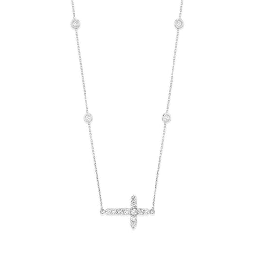 The Roberto Coin Tiny Treasures 18K White Gold Diamond Cross Necklace Pendant highlights an exquisite 18K white gold cross pendant adorned with small dazzling diamonds. The delicate chain is embellished with evenly spaced round diamond accents, enhancing the elegance of its minimalist design against a white backdrop.