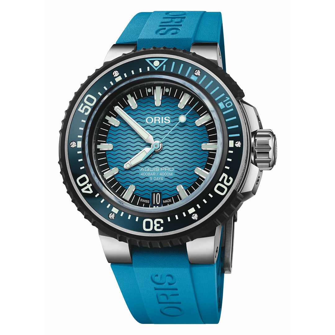 The ORIS Aquis Pro 4000m Automatic Winding 49.5mm Watch features a striking blue wavy-patterned dial, black bezel, silver hands, date window at 6 o’clock, and is paired with a blue rubber strap. This advanced diver’s watch delivers an impressive water resistance of up to 4000 metres and is set to 10:10.