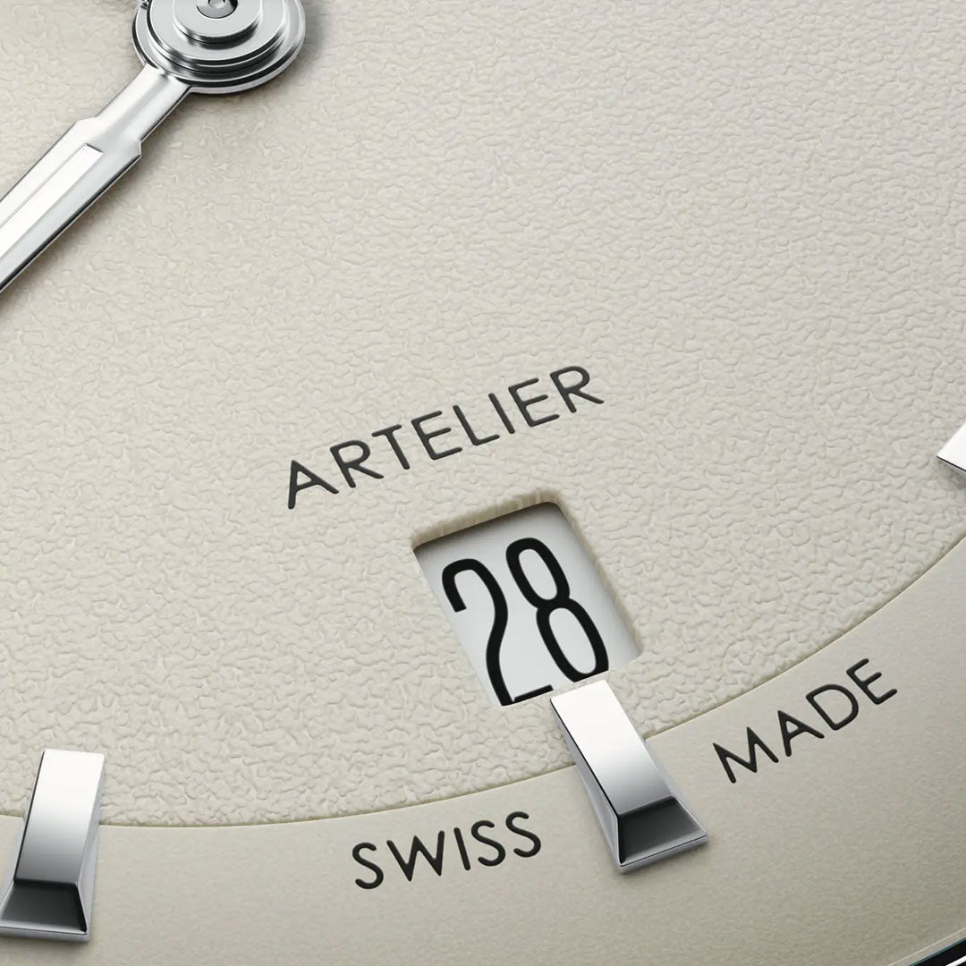 Close-up of the ORIS Artelier Date Calibre 733-1 Automatic 38mm watch face with Swiss Made movement, silver hour markers, date window at 6 o’clock showing “28,” and a textured light beige dial.