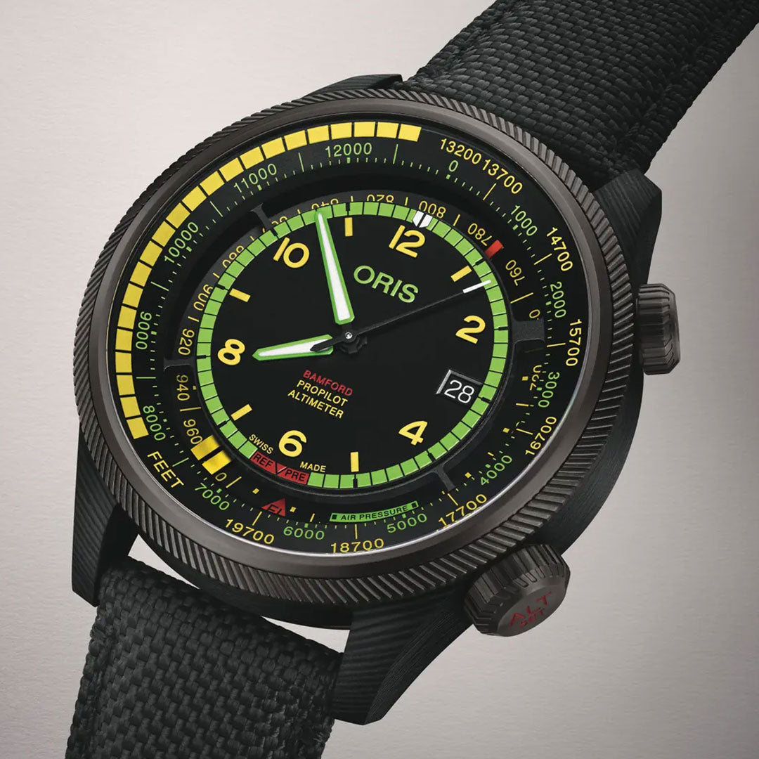 Close-up of the ORIS Propilot X BWD Limited Edition Automatic Winding 47mm Watch, featuring a black textured strap, black dial with yellow, green, and red accents, luminous Arabic numerals, and date display at 3 o’clock.