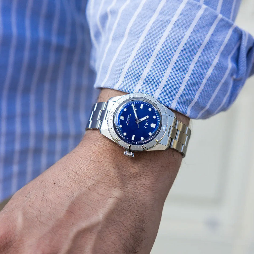 A person wearing a blue and white striped shirt displays an ORIS Divers LFP Limited Edition Automatic Winding 38mm watch on their left wrist.