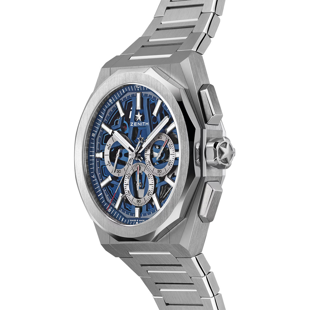 A close-up of the ZENITH Defy Skyline Chronograph Skeleton El Primero 3600SK Watch showcases a luxury silver design with metallic strap, blue dial, and sub-dials. The sleek hands sweep across its face in a 42mm steel octagonal case, featuring Zenith's logo prominently.