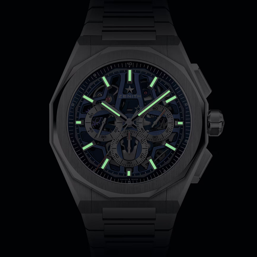 The ZENITH Defy Skyline Chronograph Skeleton El Primero 3600SK 42mm Watch by Zenith showcases a luxury design featuring luminescent green hands and markers on a dark dial with visible intricate gears, an octagonal bezel, and a metallic bracelet, epitomizing high-frequency automatic chronograph precision.