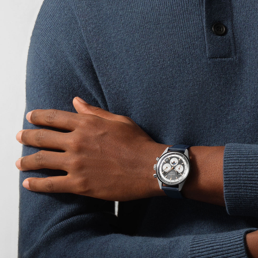 A person wearing a dark blue sweater crosses their arms, showcasing a ZENITH Chronomaster Original El Primero 3610 Automatic Chronograph 38mm Watch with a blue strap and silver dial on their left wrist.