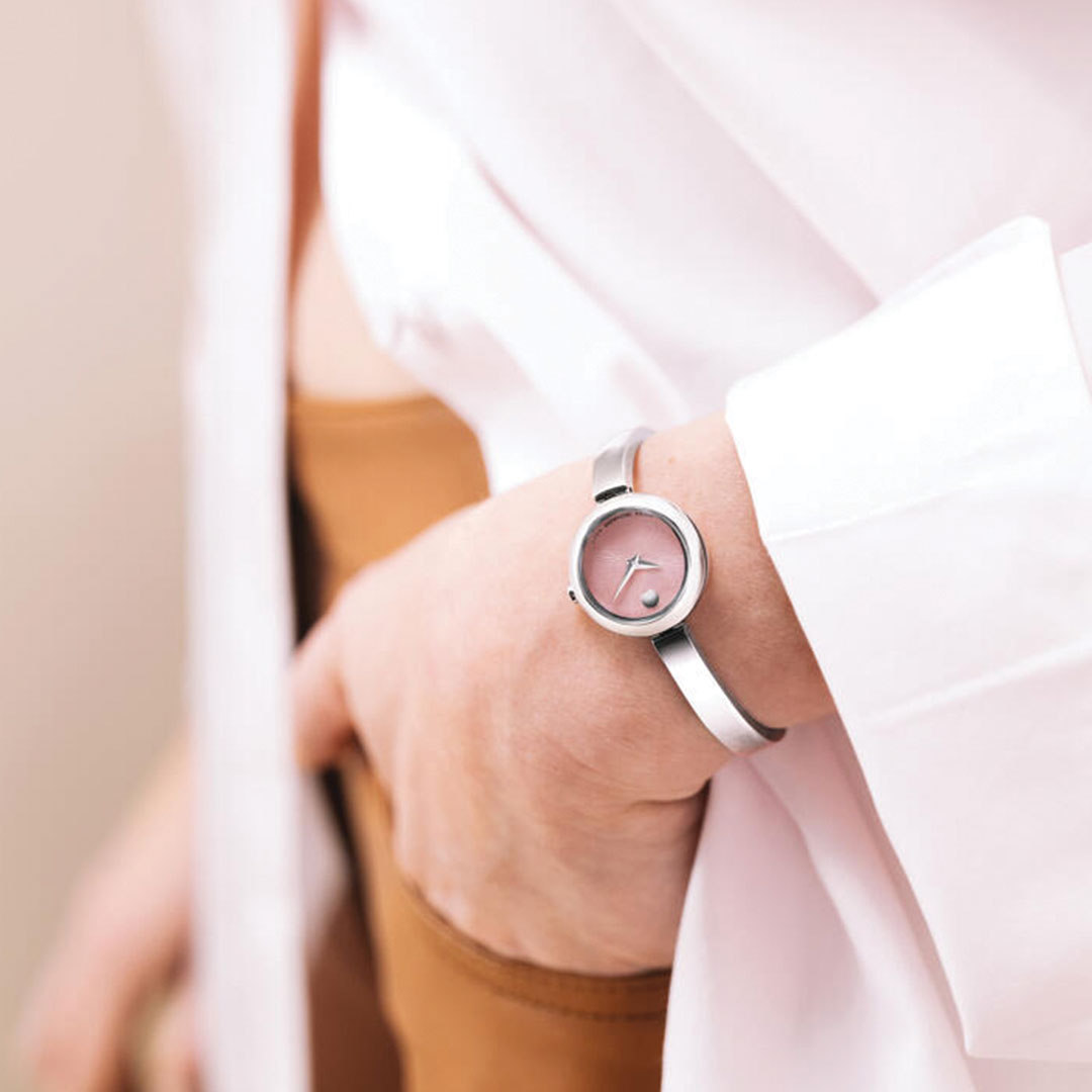 A person in a white shirt and tan pants with one hand in their pocket showcases a Movado Museum Bangle Quartz 21.5mm Watch on their wrist.