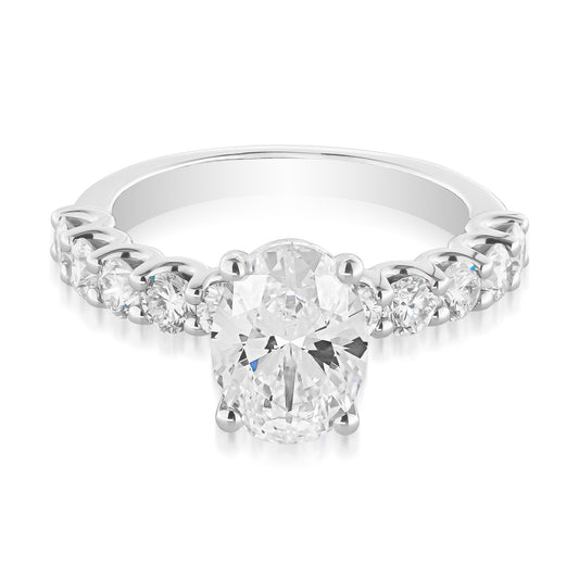 The Raffi&Co® 14K White Gold Oval Solitaire Diamond Engagement Ring features a breathtaking oval diamond solitaire as its centerpiece, complemented by smaller round diamonds along the band. The detailed setting enhances the brilliance of the 2.20-carat diamond, creating a stunning contrast against the white gold metal.