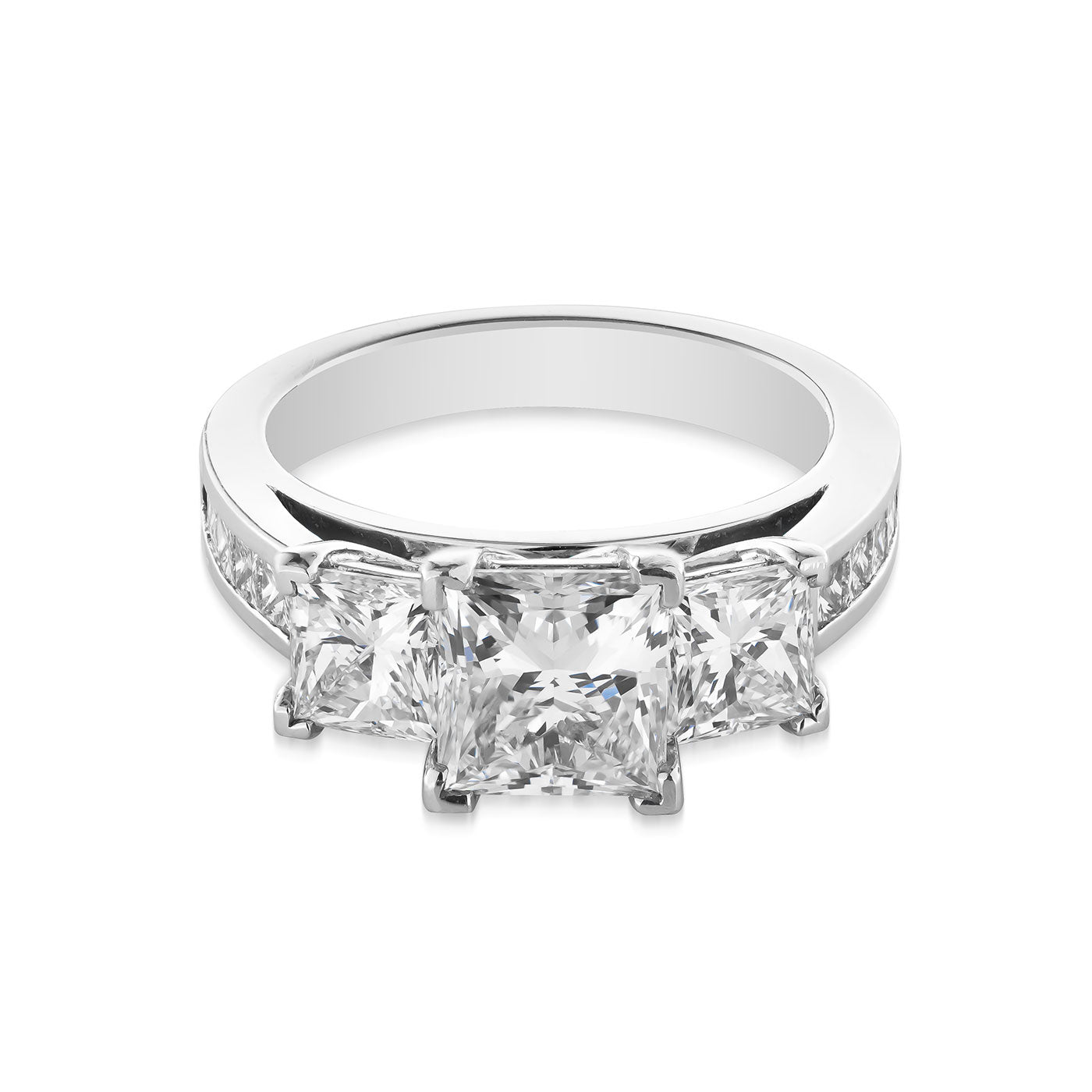 The Raffi&Co.® 14K White Gold Princess Cut Three Stone Diamond Engagement Ring features a breathtaking central princess-cut diamond, complemented by two smaller diamonds on each side. The 14K white gold band is embellished with additional smaller diamonds, adding an extra touch of elegance.