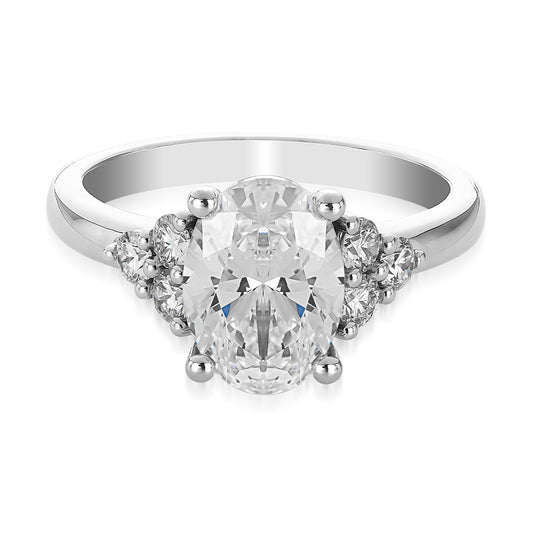 The Raffi&Co.® 14K White Gold Oval Three Stone Lab Diamond Engagement Ring features a captivating design with a stunning center diamond flanked by two smaller round diamonds, all set on a smooth, polished band to enhance its elegant and timeless appeal.