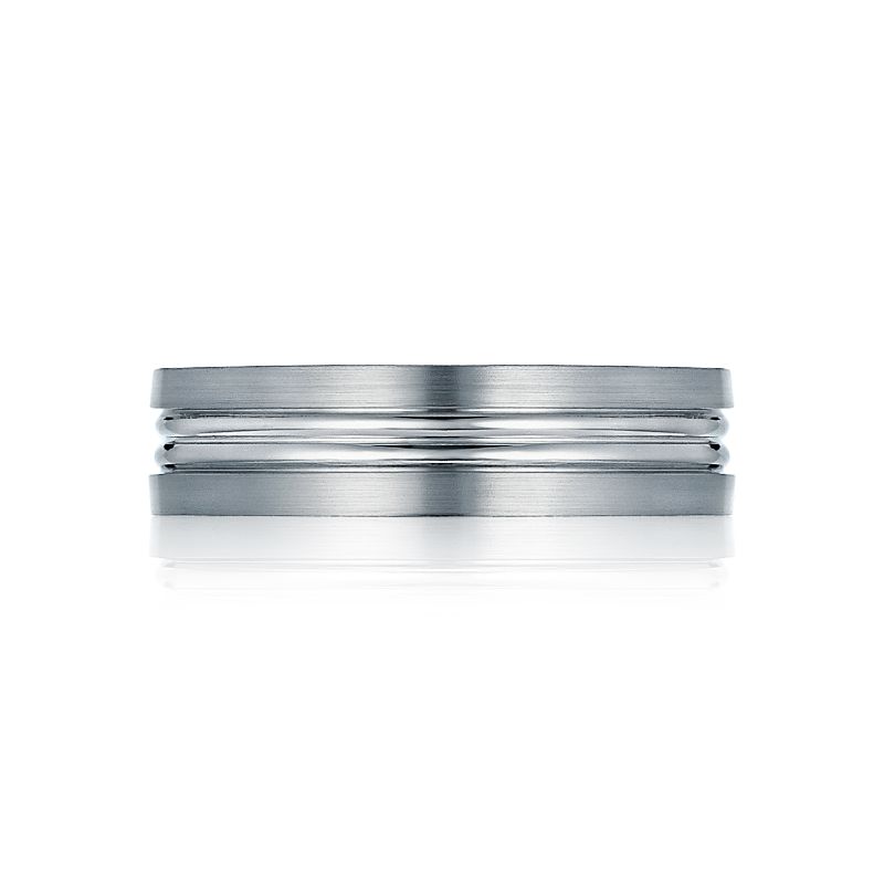 The Tacori Classic Satin Finish 18K White Gold Men's Wedding Band showcases a sleek and sophisticated design. It features a gentlemen's band as the central accent, set on a reflective surface against a white backdrop. This ring merges brushed and shiny finishes to achieve an elegant, minimalist style.
