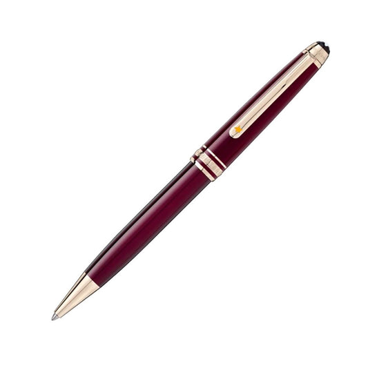A stylish Montblanc Meisterstuck Le Petit Prince Classique ballpoint pen with gold accents and a smooth clip is set diagonally against a white background, highlighting its sophisticated burgundy design and intricately detailed cap.