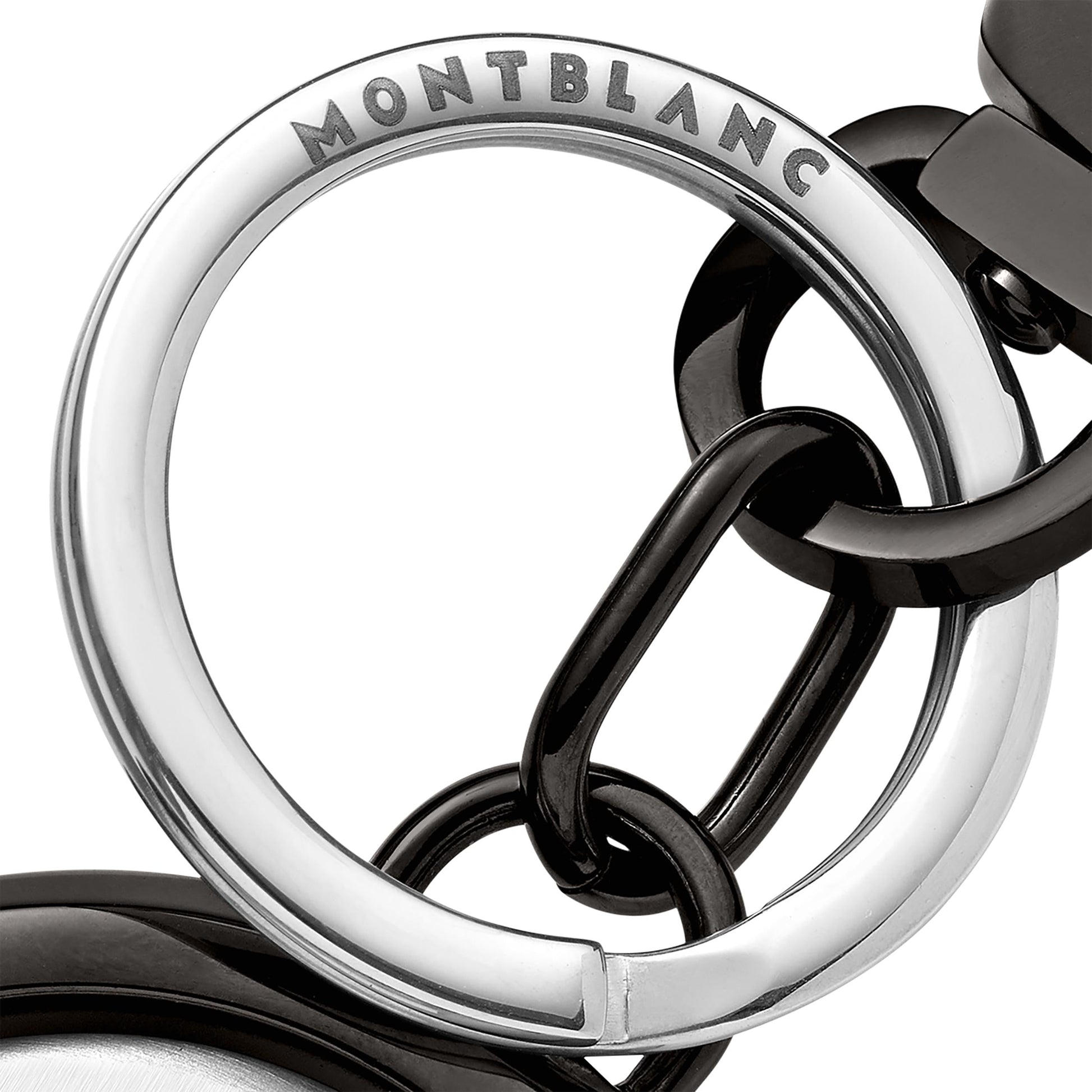 Close-up of a Montblanc Meisterstuck Spinning Emblem Key Fob, featuring a shiny silver circular ring engraved with the Montblanc name, connected to black rings. The design highlights a modern and elegant combination of silver and black elements centered around its spinning emblem.