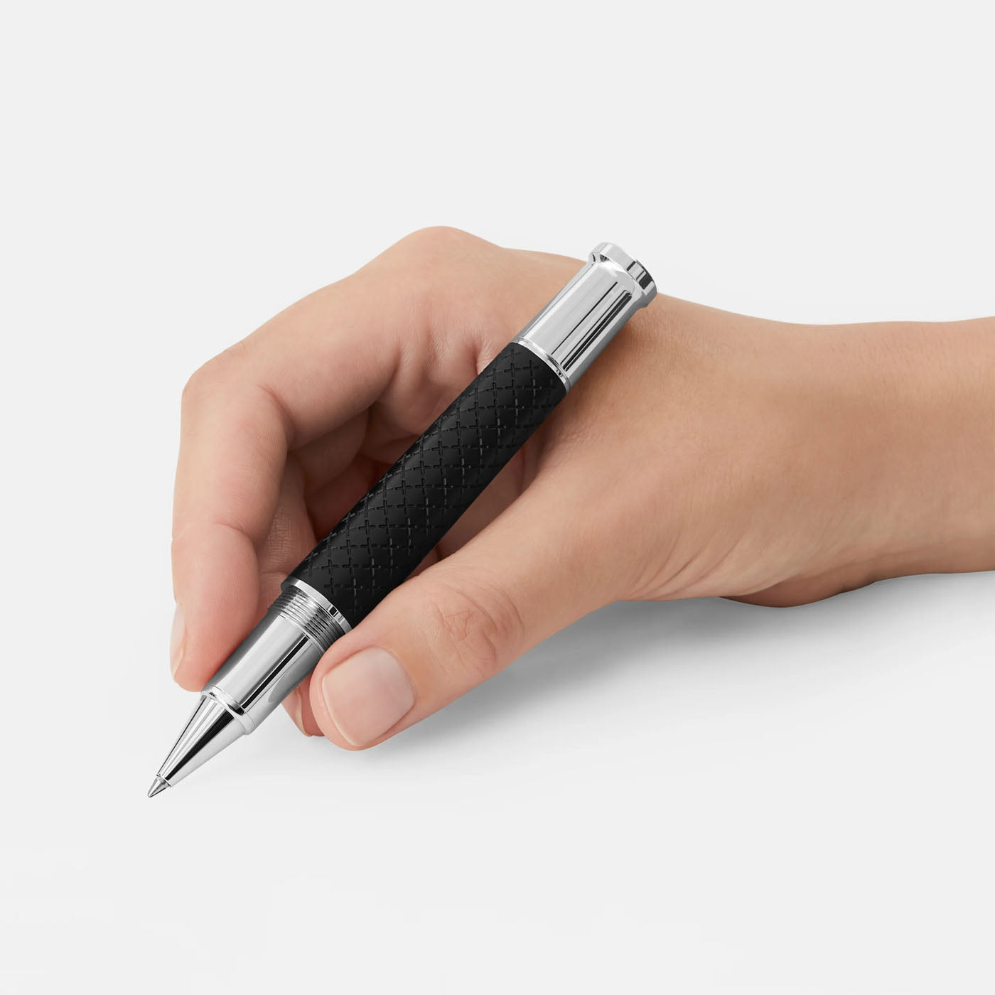 A hand holds the Montblanc Writers Edition Homage to Robert Louis Stevenson Limited Edition Rollerball Pen, featuring a sleek black design with a textured grip and silver accents, against a plain white background. Poised for writing, this pen captures the elegance reminiscent of Robert Louis Stevenson's "Treasure Island.