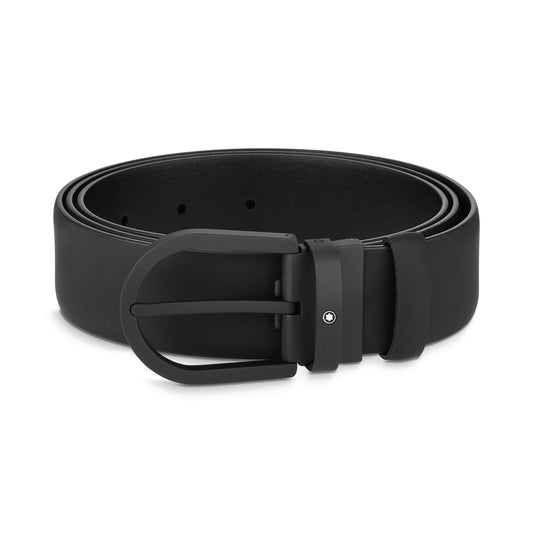 A Montblanc Horseshoe Leather Belt in black, featuring a matte black buckle, is rolled neatly and secured with a small loop. The minimalist design includes a subtle single metal stud near the buckle for extra detail.
