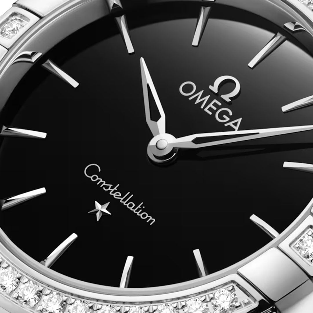 Close-up of the OMEGA Constellation Quartz 28mm Watch, a stainless steel luxury timepiece with a black dial, silver hands and markers, diamond bezel, and prominent OMEGA branding on the face.