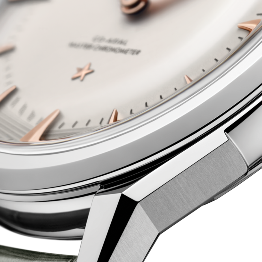 Close-up of an OMEGA Constellation Observatory Co-Axial Master Chronometer 39.4mm watch dial featuring a light-colored face, rose gold-tone indices and hands, and a metal case with a brushed finish.