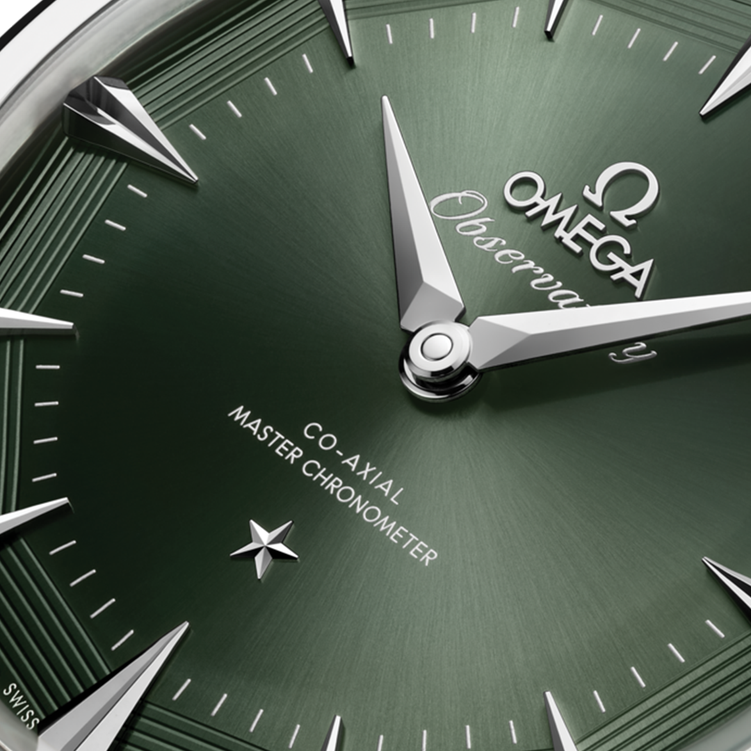 Close-up of the green dial on an OMEGA Constellation Observatory Co-Axial Master Chronometer 39.4mm Watch, featuring silver hands, hour markers, a star emblem, and “Co-Axial Master Chronometer” text.