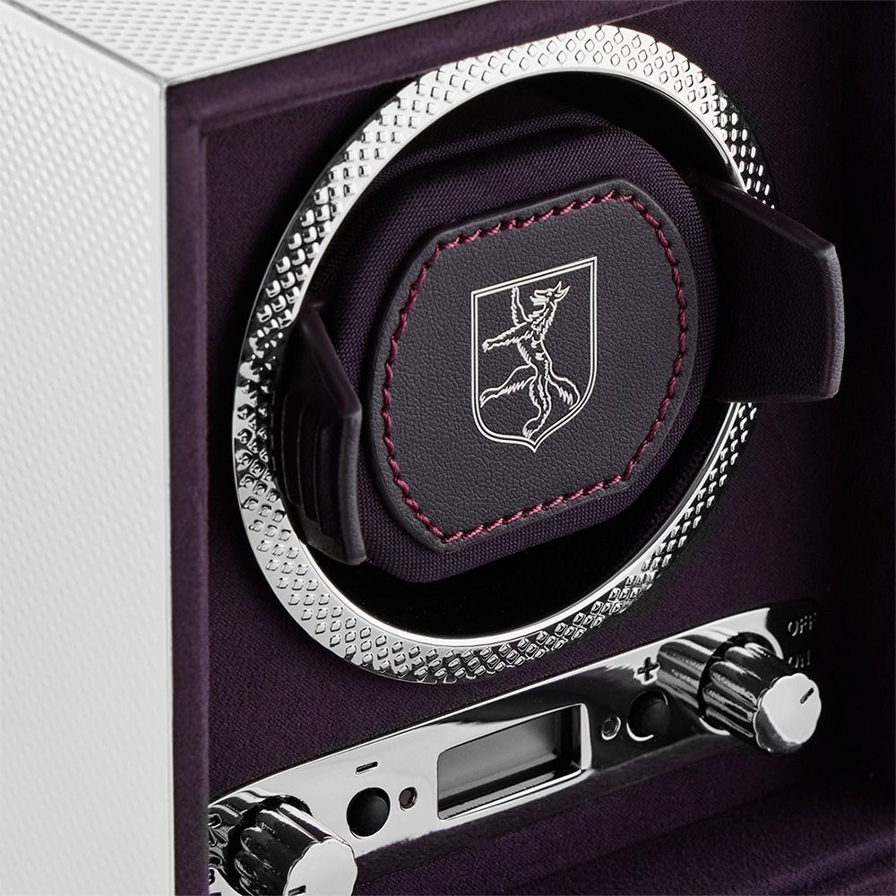 Close-up of the WOLF 1834 Single Watch Winder Silver by WOLF, crafted from luxurious ebony macassar wood and designed with a textured metal ring, padded holder adorned with the embroidered WOLF crest, and precise control knobs set on a sleek, dark purple and silver panel—an exceptional statement piece among luxury watch accessories.