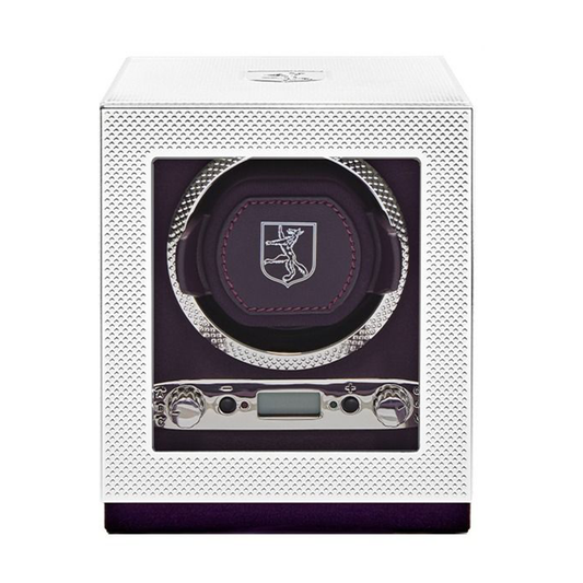 The WOLF 1834 Single Watch Winder Silver by WOLF features a white, textured exterior with a glass front that showcases a purple interior, a circular watch holder adorned with the brand’s stylized logo, and a digital control panel at the bottom offering power reserve setting options.
