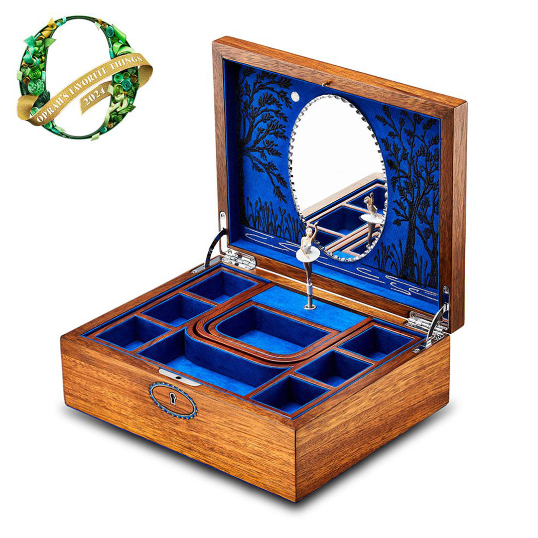 The WOLF 1834 Ballet Musical Jewellery Box by WOLF features an open lid revealing several compartments lined with blue velvet, a small circular mirror inside, and a decorative leaf pattern. A "Favorite Things 2023" badge is proudly displayed in the top left corner, celebrating Swan Lake's elegant charm.