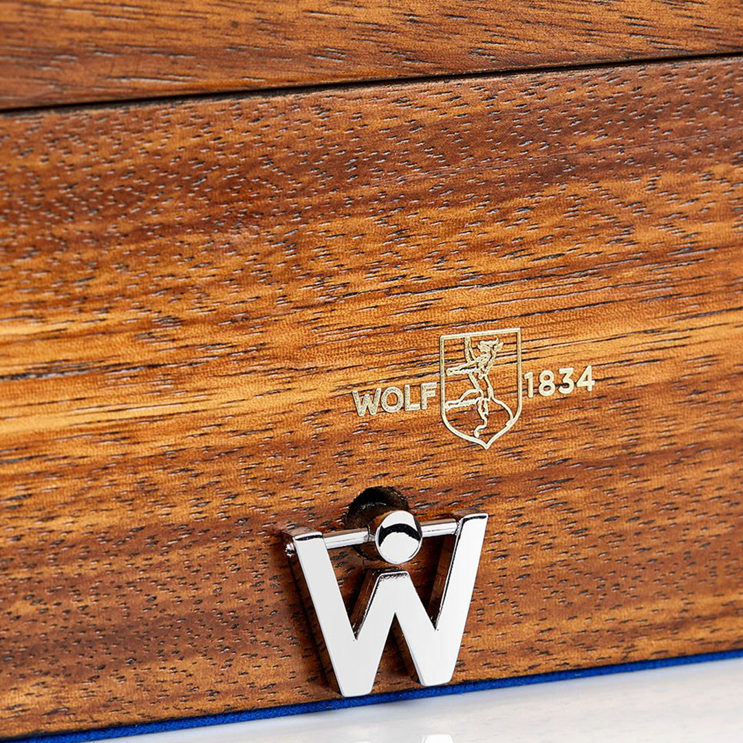 Close-up of the WOLF 1834 Ballet Musical Jewellery Box, commemorating WOLF's 190th anniversary, with engraved text "WOLF 1834" and a shield logo. Below, an elegant metallic clasp shaped like the letter "W" evokes the grace of Swan Lake.