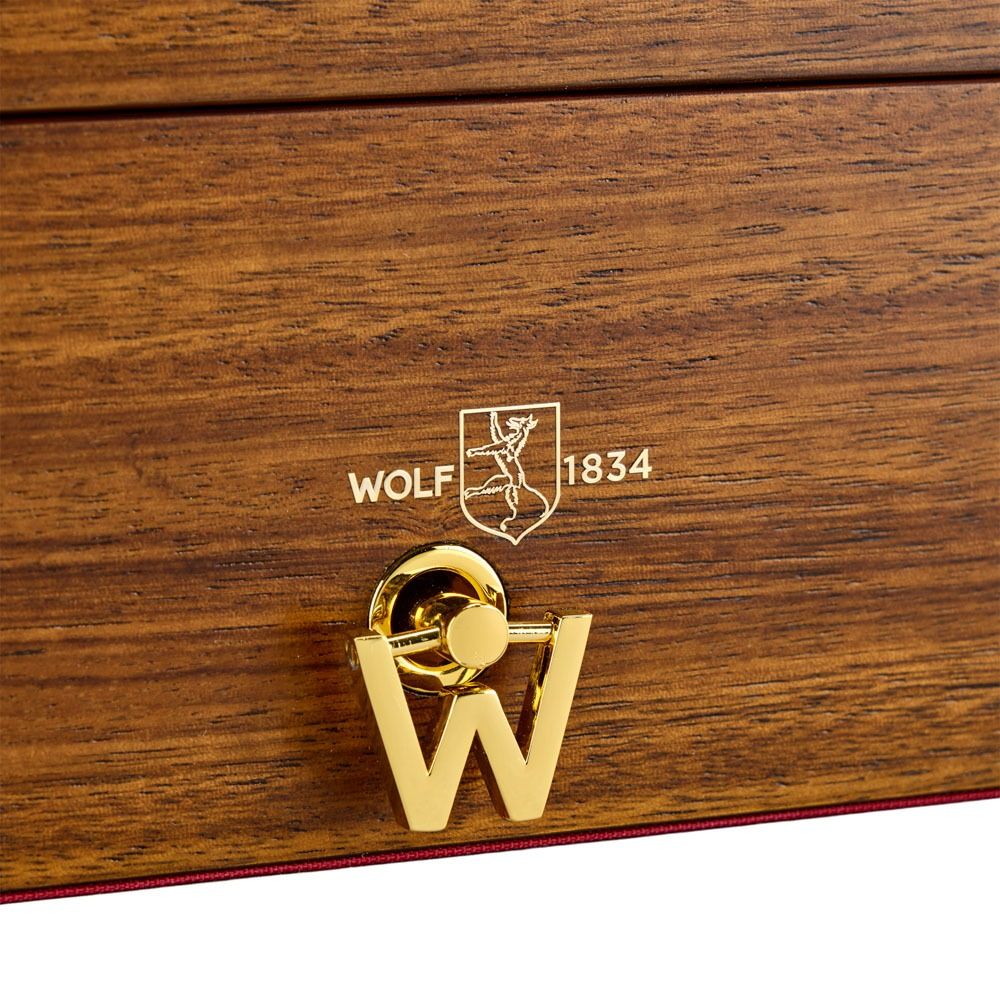 Close-up of the WOLF 1834 Nutcracker Musical Box Jewelry Box in walnut, featuring a gold “W” clasp and the engraved WOLF logo above the text “WOLF 1834.”.