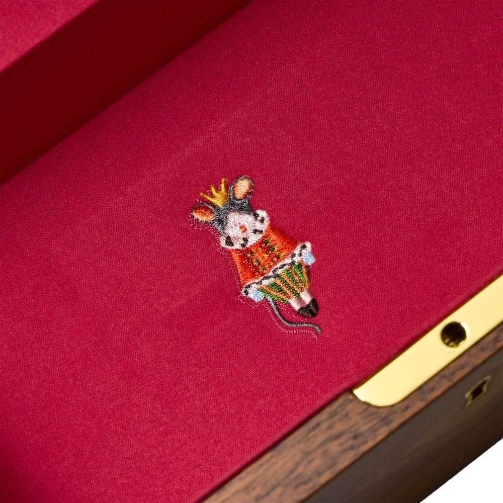 A small embroidered mouse wearing a crown and red dress is stitched onto red fabric inside the WOLF 1834 Nutcracker Musical Box Jewelry Box Walnut by WOLF, which features a gold clasp and evokes the charm of a classic musical jewelry box.