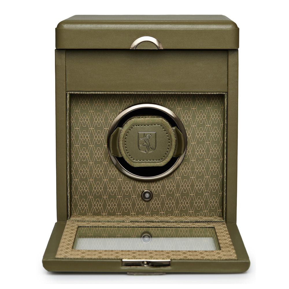 The WOLF 1834 Earth Single Watch Winder, crafted by WOLF, displays a stunning green design with an open lid that reveals a detailed geometric pattern. It includes a patented lock-in dynamic cuff and features a transparent base window along with a cushioned compartment to securely hold your watch.