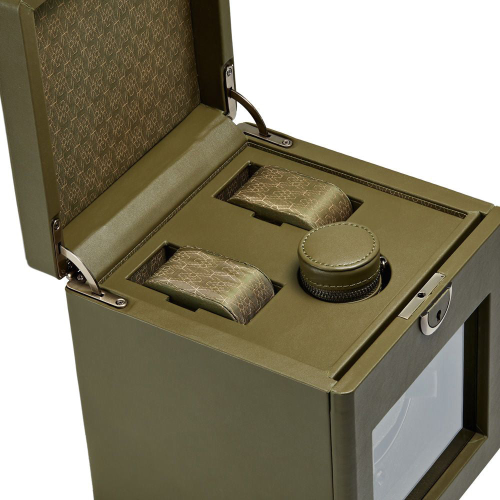The WOLF 1834 Earth Single Watch Winder, by the renowned brand WOLF, is a stylish green box with a textured pattern. It features watch compartments lined with matching fabric and includes Bluetooth capability. Its design incorporates a lock mechanism and a transparent front section for easy viewing, highlighting its patented innovation in dynamic design.