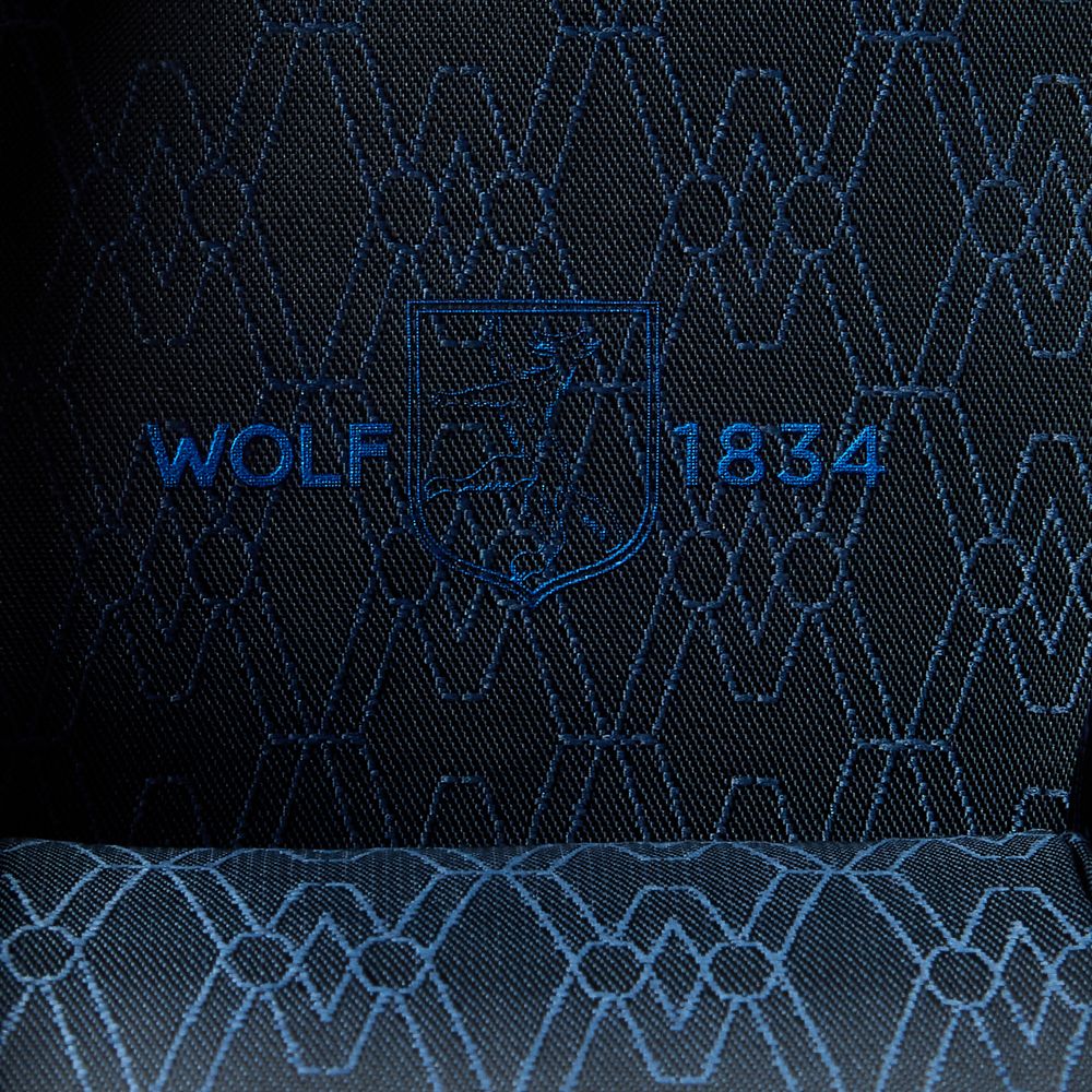 Close-up of dark fabric with a geometric hexagonal pattern and blue "WOLF 1834" embroidery with a shield emblem—crafted for the WOLF 1834 Earth Triple Watch Roll.
