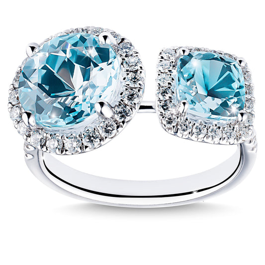 The Raffi&Co.® 18K White Gold Fashion Ring showcases two large, oval blue topaz stones encircled by a halo of sparkling clear diamonds. Its split shank design features a modern, open-ended style for elegance and sophistication.