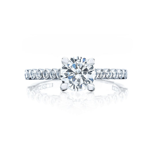 The Tacori Sculpted Crescent 18K White Gold Round Brilliant Semi Mount Solitaire Engagement Ring with Diamond Band exemplifies the timeless allure of diamond engagement rings. Featuring an elegant design, this piece showcases a large round center diamond surrounded by smaller diamonds along the band. Displayed against a white background with a subtle reflection beneath, it exudes sophistication and style.