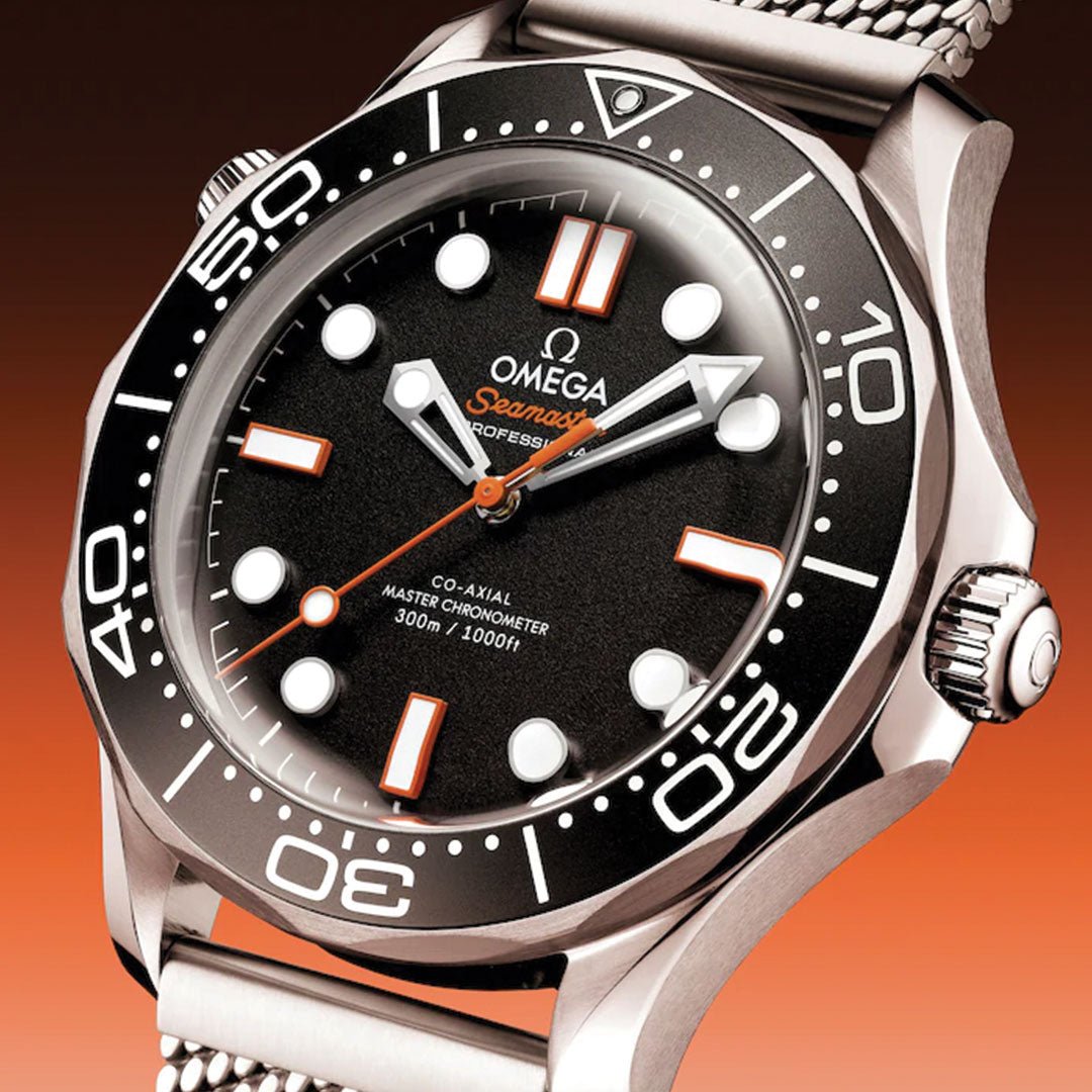 Close-up of the OMEGA Seamaster Diver 300M Co-Axial Master Chronometer 42mm Watch, featuring a black dial, white and orange hour markers, and a stainless steel mesh strap against a gradient orange background.