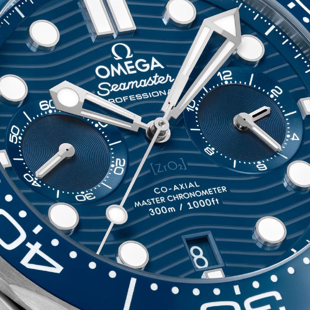 Close-up of the OMEGA Seamaster Diver 300M Co-Axial Master Chronometer Chronograph 44mm watch face, showing a blue patterned dial, silver and white hands, two subdials, and "Co-Axial Master Chronometer 300m / 1000ft" above the date window.