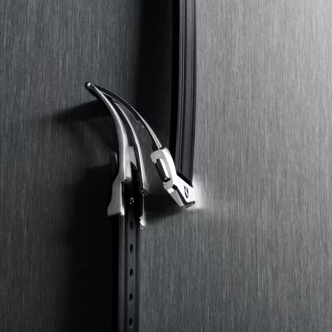 A close-up of two black leather belts with silver buckles linked together, displayed vertically against brushed metal, channeling the refined aesthetics of the OMEGA Seamaster Diver 300M Co-Axial Master Chronometer 42mm Watch by OMEGA.