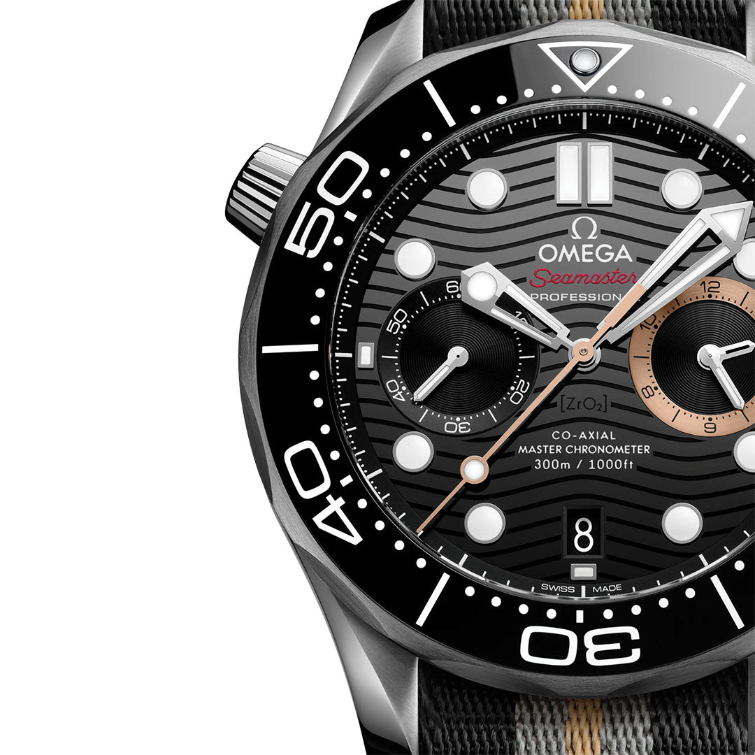 Close-up of the OMEGA Seamaster Diver 300M 007 First Light Edition Co-Axial Master Chronometer Chronograph 44mm Watch, highlighting its black wave-patterned dial, bold white hour markers, subdials, and rotating bezel. The OMEGA Co-Axial Master Chronometer hands and chronograph features are prominently displayed.