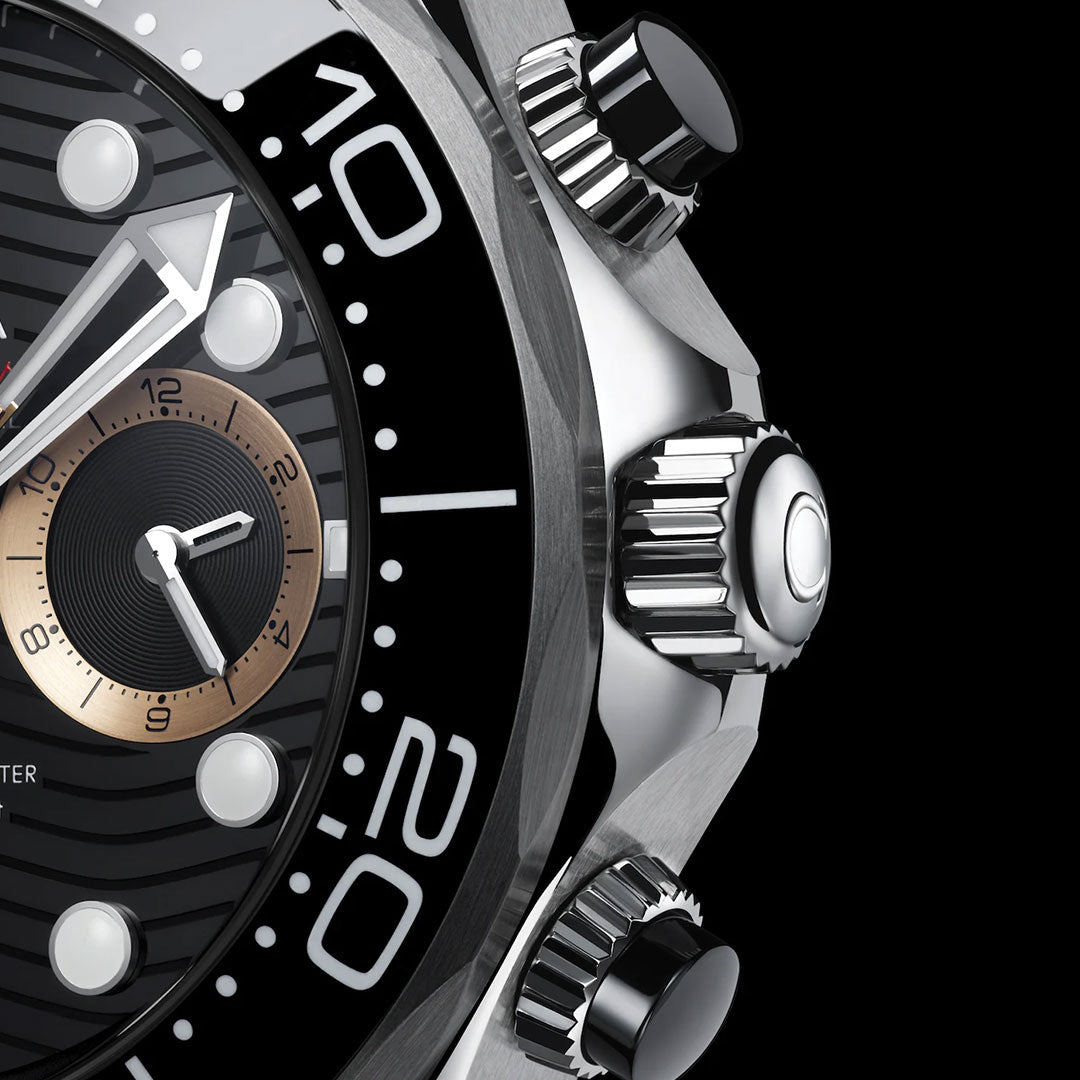 A close-up of the OMEGA Seamaster Diver 300M 007 First Light Edition Co-Axial Master Chronometer Chronograph 44mm Watch, highlighting part of its black dial with white markings, a gold subdial, textured bezel, and two metal crown buttons on the side, set against a black background.