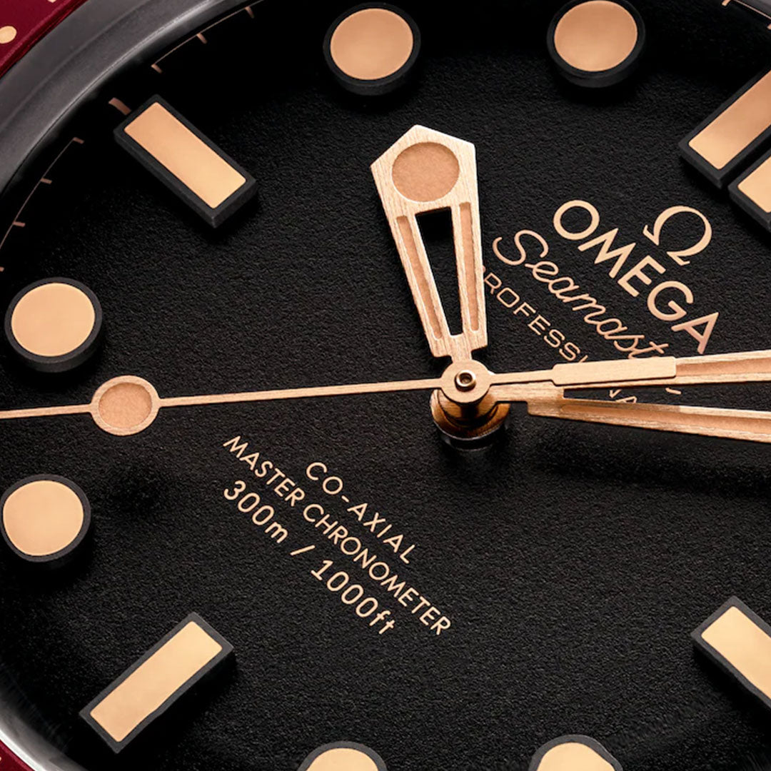 Close-up of the OMEGA Seamaster Diver 300M Co-Axial Master Chronometer 42mm watch, showing gold hands and markers on a black dial, with "Co-Axial Master Chronometer 300m/1000ft" and the iconic OMEGA Seamaster logo.
