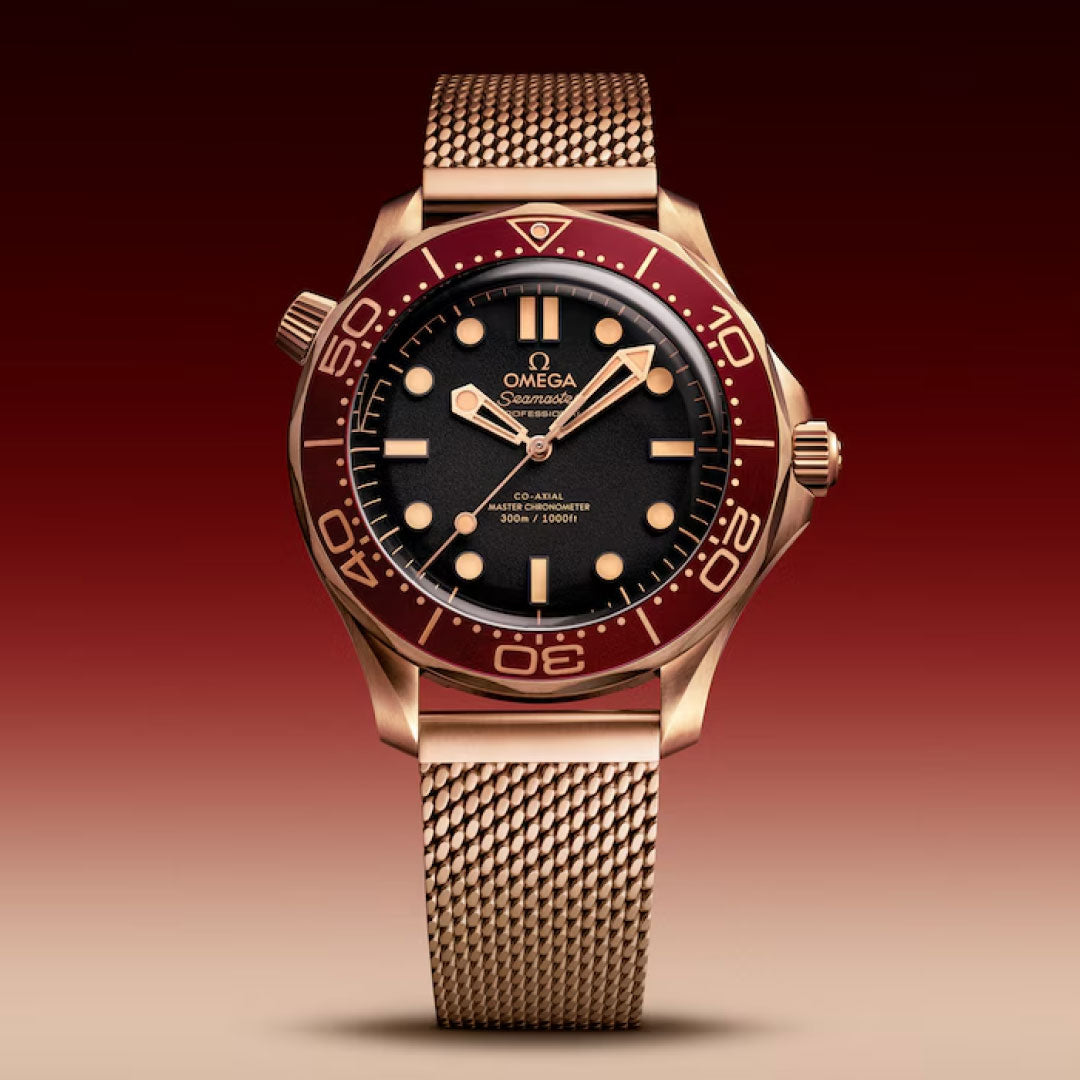 The OMEGA Seamaster Diver 300M Co-Axial Master Chronometer 42mm Watch features a burgundy bezel, black dial, gold hour markers, and rose gold mesh strap—exuding refined sophistication against a gradient burgundy backdrop.