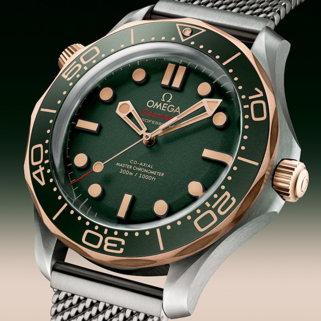 The OMEGA Seamaster Diver 300M Co-Axial Master Chronometer 42mm Watch showcases a green dial, gold hour markers, and mesh strap. It features a stainless steel case with a 9K Bronze Gold bezel, alongside "Omega Seamaster" and "300m / 1000ft" details—a true masterpiece.