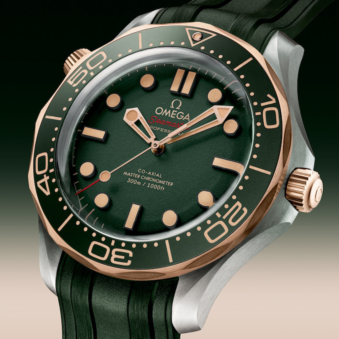 The OMEGA Seamaster Diver 300M Co-Axial Master Chronometer 42mm Watch exemplifies luxury with its green dial, gold hands/markers, and a ceramic bezel with gold numerals in a stainless steel case, all powered by Calibre 8806.