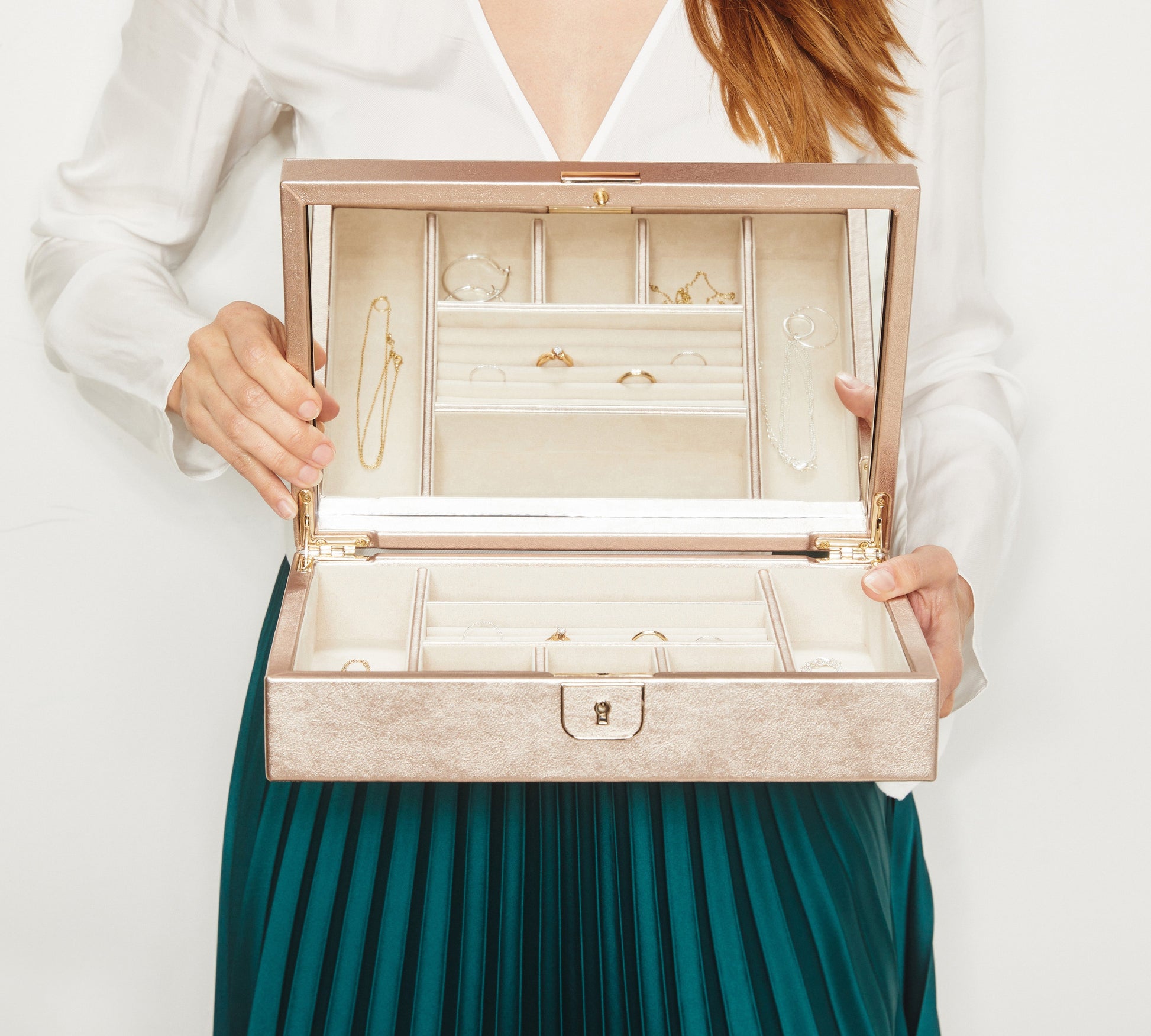 A person holds an open WOLF 1834 Palermo Medium Jewellery Box featuring LusterLoc™ technology, ensuring their rings, bracelets, and necklaces remain pristine. They are dressed in a white blouse paired with a green pleated skirt.