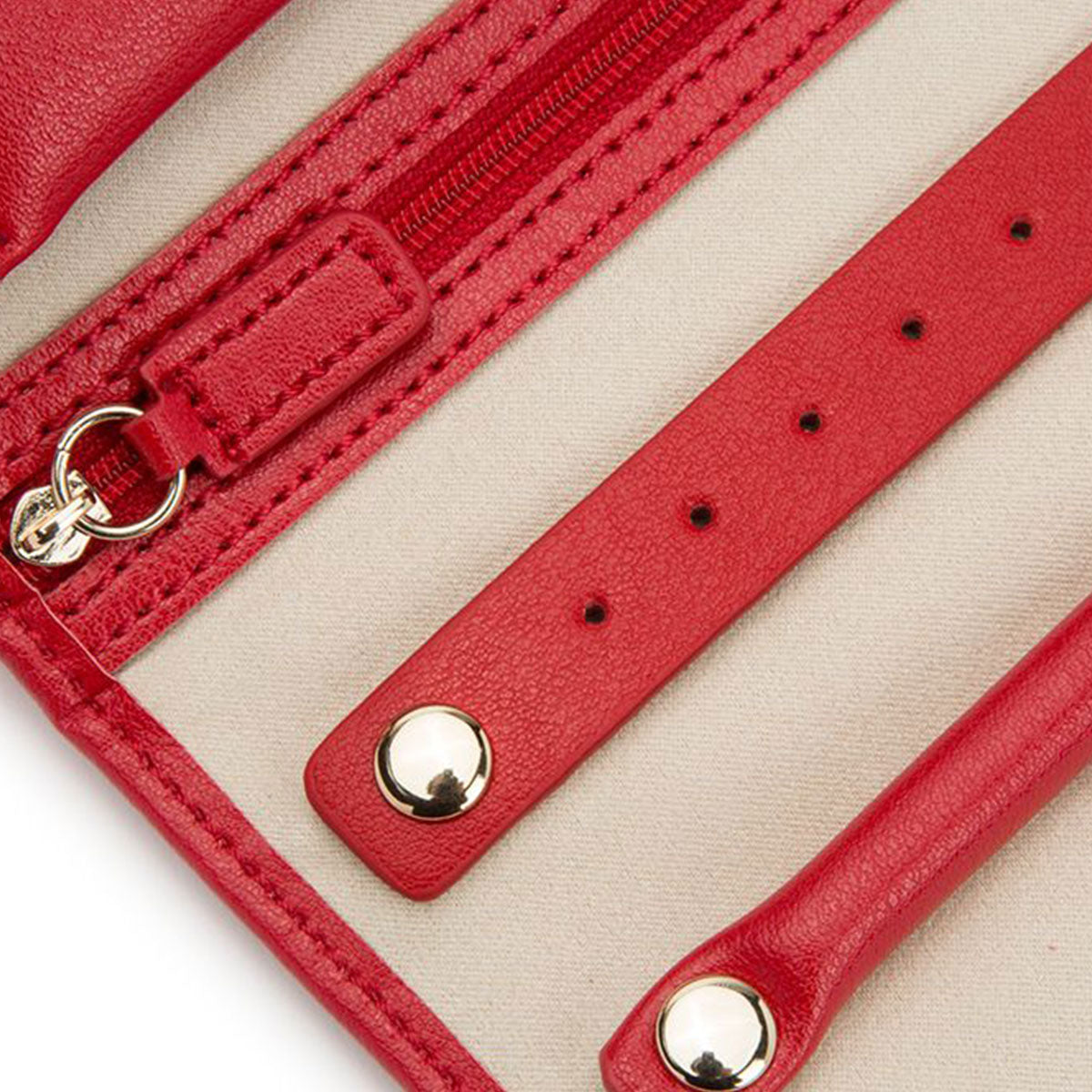 Close-up of the WOLF 1834 Palermo Jewellery Roll, showcasing its luxurious red leather exterior with gold snap buttons and a zipper. The open design reveals a cream-colored lining and multiple straps, making it ideal for travel storage. Perfect as a leather jewelry case, this roll keeps your items secure and organized on the go.