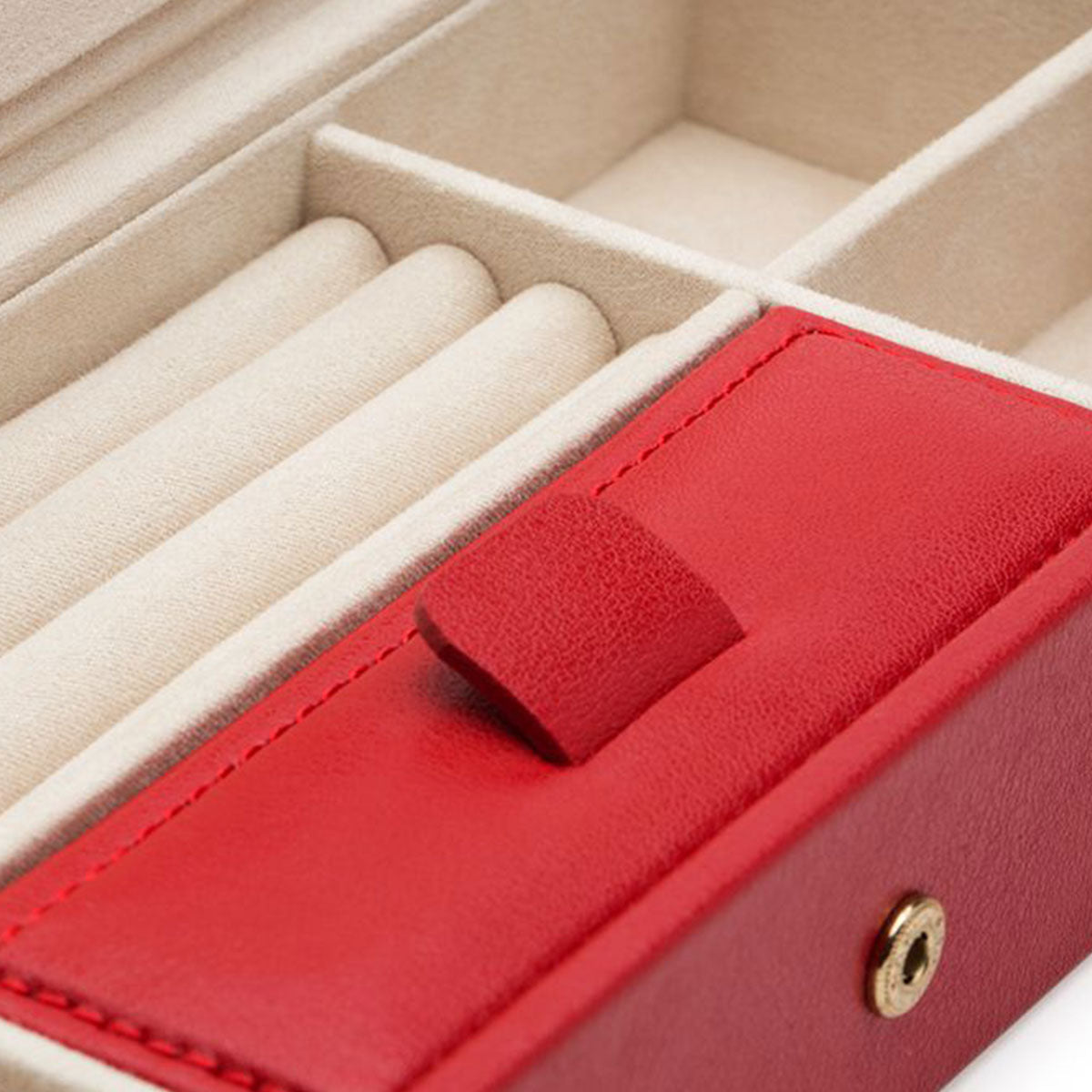 Here's a revised version of the sentence using the provided product data:

Close-up of the elegant WOLF 1834 Palermo Safe Deposit Box encased in a luxurious red leather cover. The beige interior is thoughtfully designed with multiple compartments for organizing jewelry, featuring ring slots and larger sections. A snap button is prominently displayed on the lid, while the LusterLoc anti-tarnish lining enhances its sophisticated appeal.